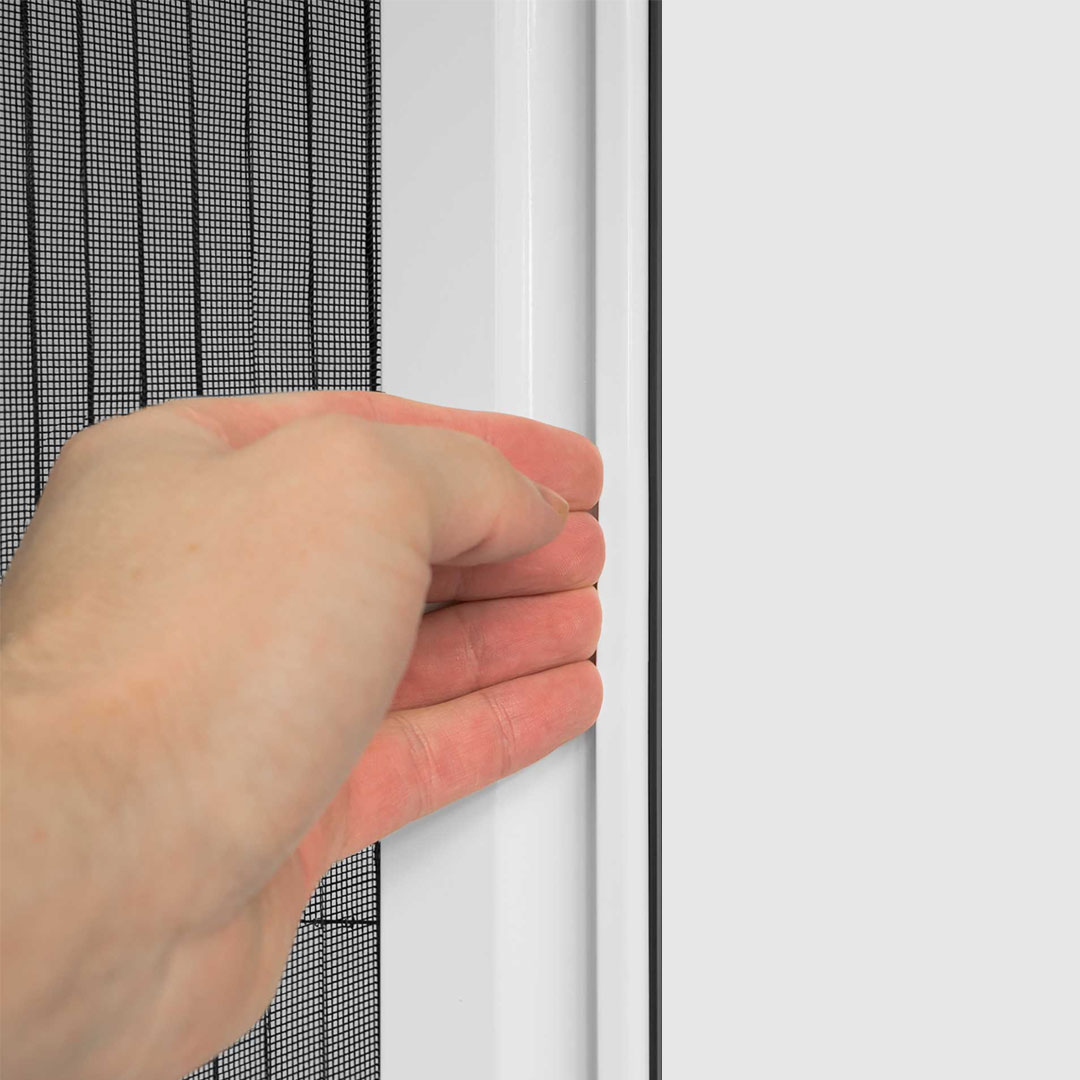 Hand zieht Fliegengitterrahmen neben Fenster mit weißem Rahmen