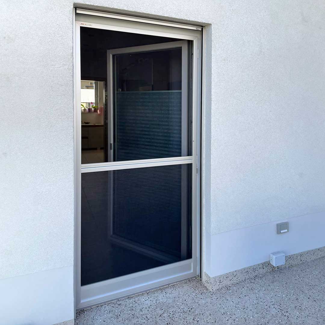 Fliegengittertür, geschlossen, an einer weißen Hauswand montiert.