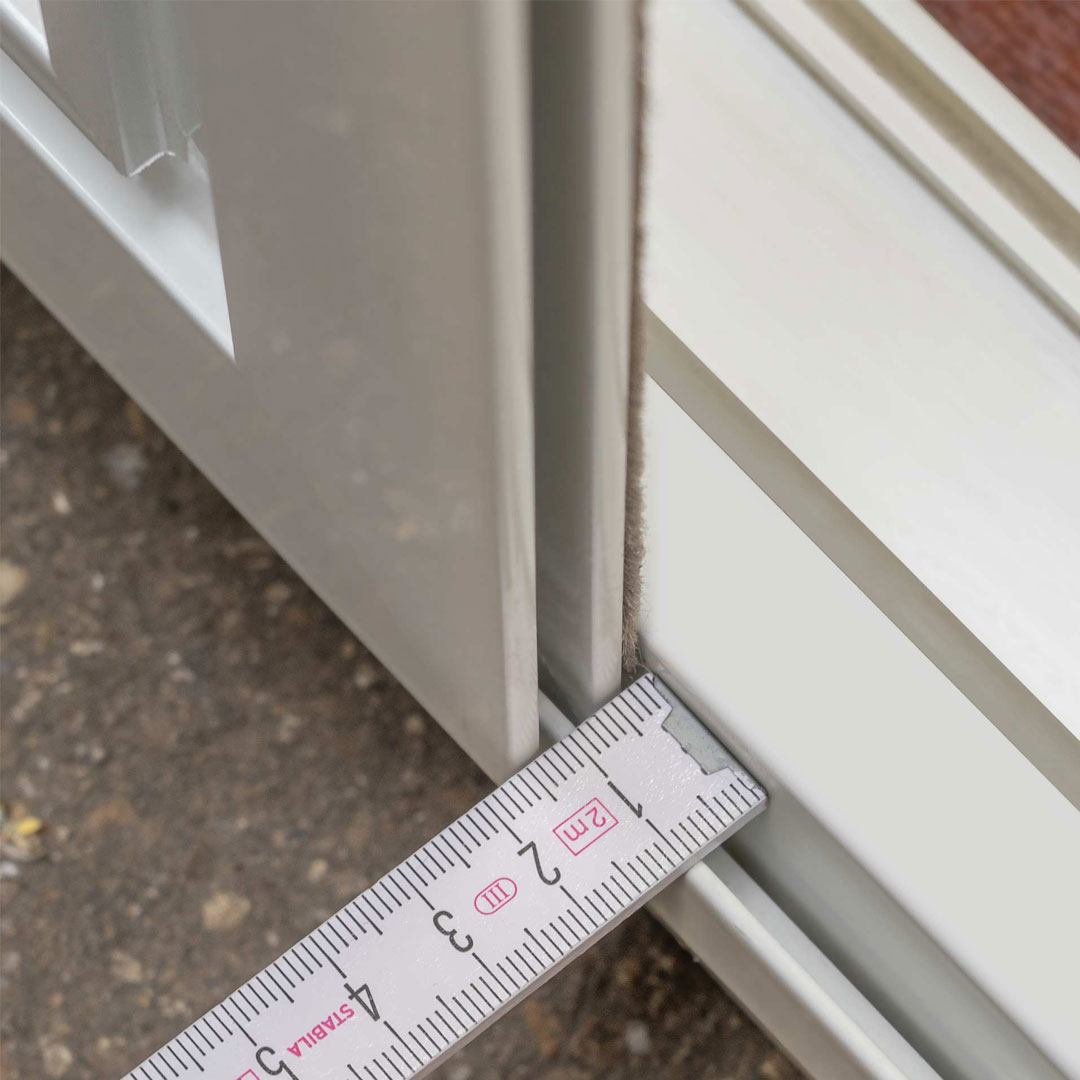 Zollstock misst Spaltbreite zwischen Fensterrahmen und Fliegengitter