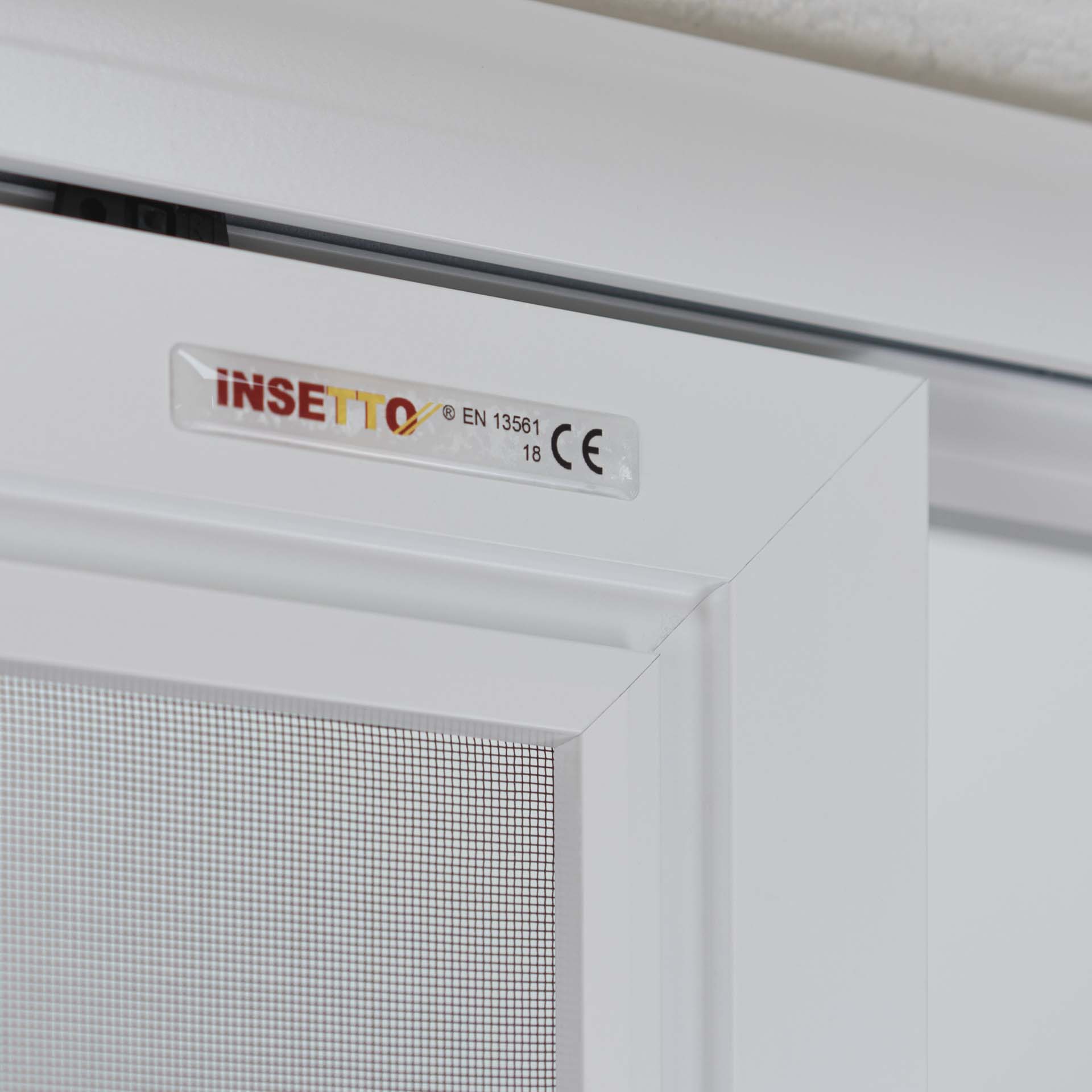 Fliegengitter an einem weißen Fensterrahmen innen.