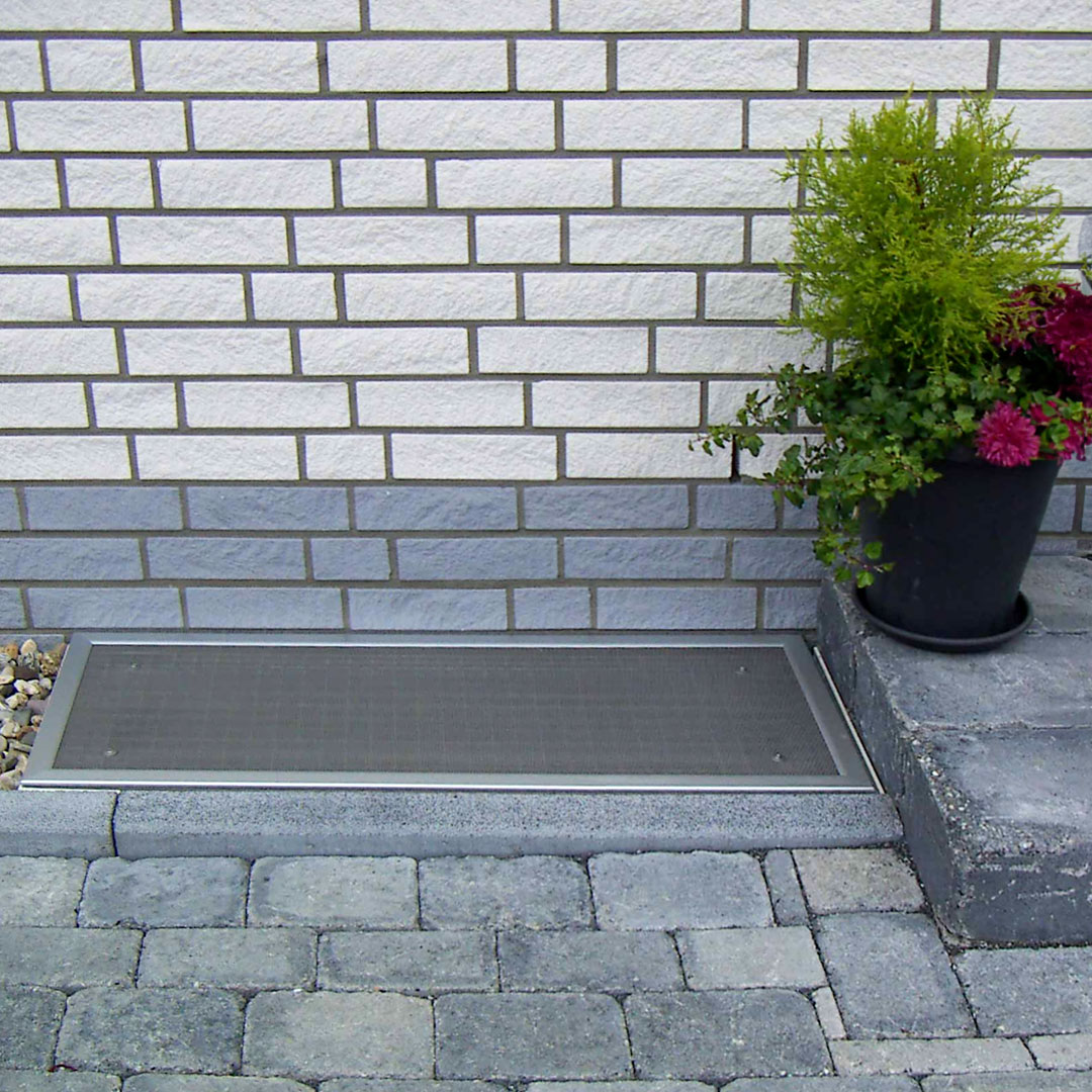 Lichtschachtabdeckung im Außenbereich neben einer Pflanze.