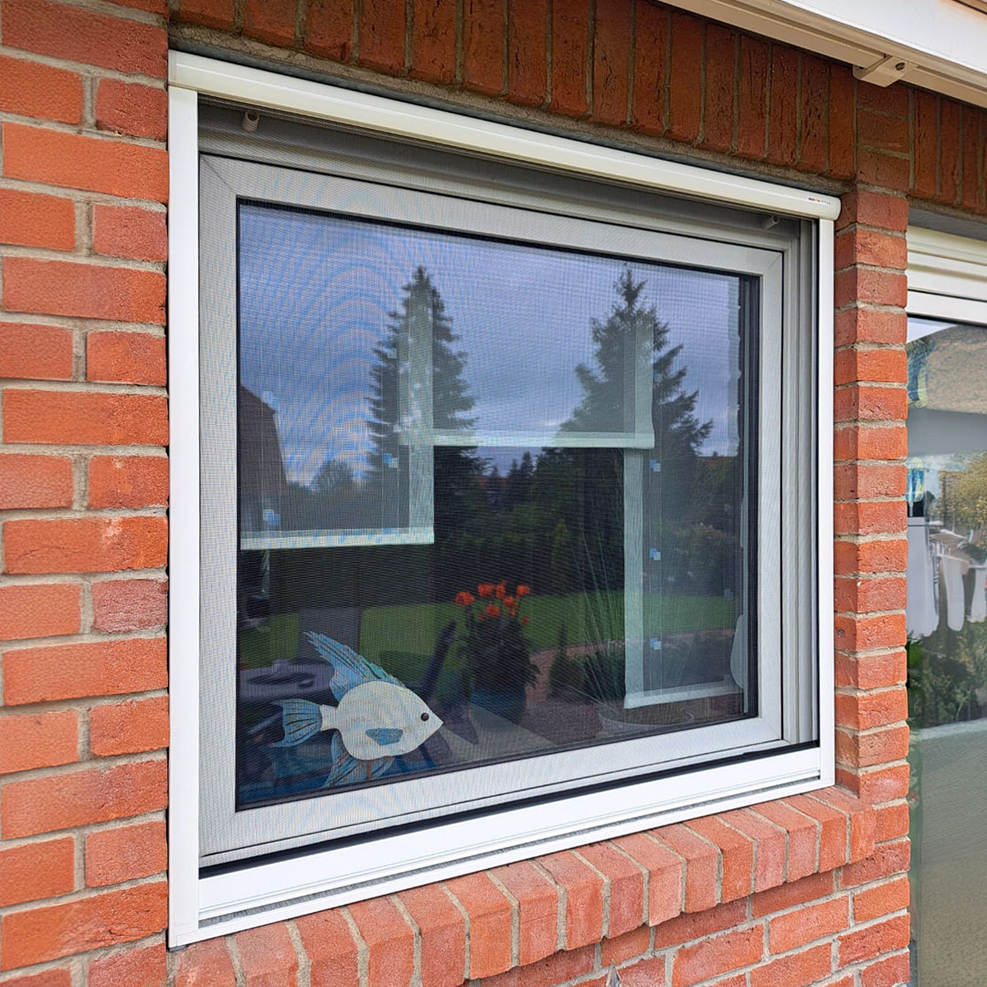 Fliegengitter an Fenster in roter Ziegelwand