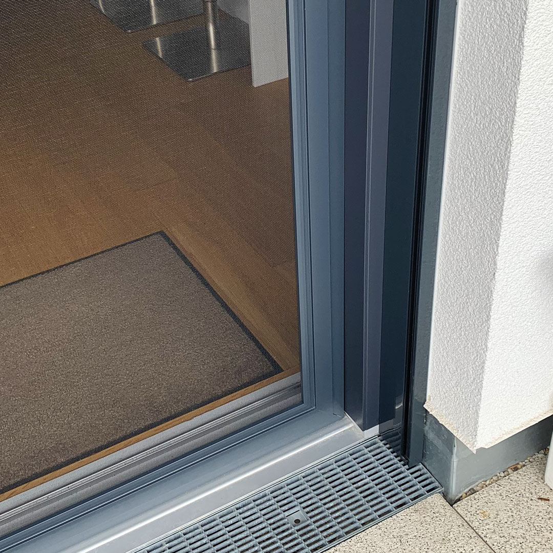 Fliegengitterschiebetür an einem modernen Gebäude montiert