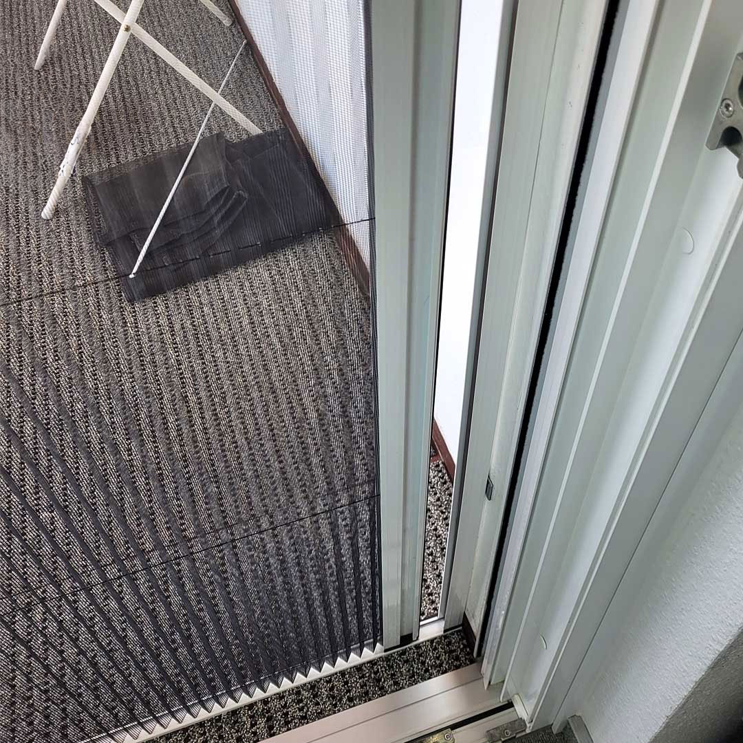 Plissee-Fliegengittertür führt zu Terrasse mit Teppichboden