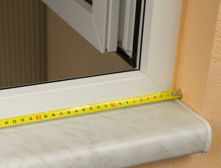 Maßband misst Fensterbrettbreite.