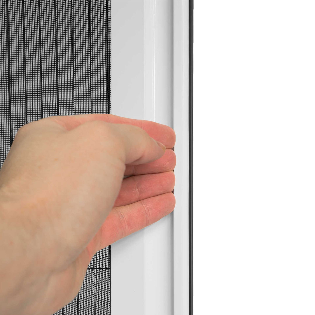 Hand zieht Fliegengitter im weißen Fensterrahmen zu.