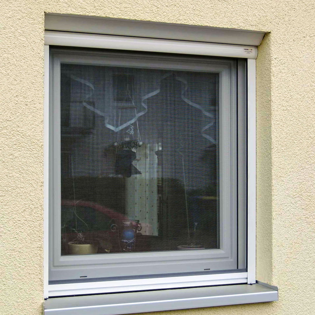 Fenster, mit Fliegengitter ausgestattet, in beiger Hauswand.