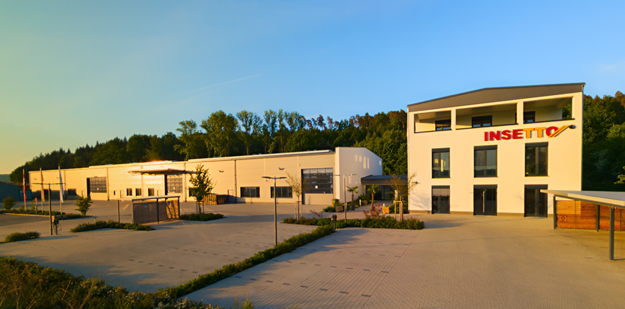 Insetto-Gebäude mit Logo, davor Parkplätze.