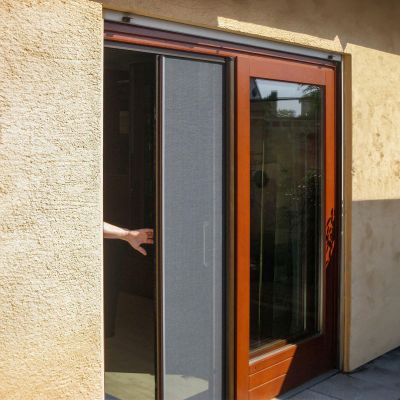 Insektenschutzrollo wird geöffnet an Terrassentür befestigt