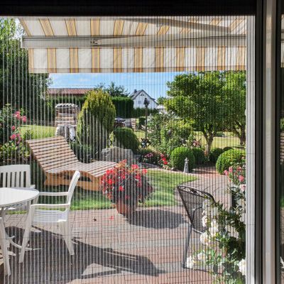 Fliegengitter trennt Wohnzimmer von Gartenbereich.