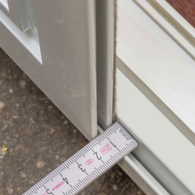 Zollstock misst Spaltbreite zwischen Fensterrahmen und Fliegengitter