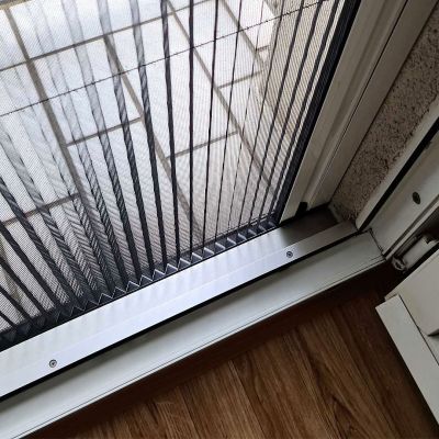 Geschlossenes Insektenschutzplissee vor einer Terrassentür auf Holzboden.