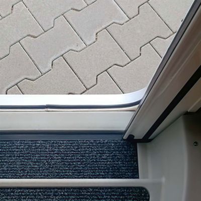 Schiene von Insektenschutzplisseetür vor gepflastertem Boden