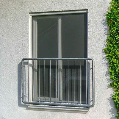 Fliegengitter montiert an Fenster in Hauswand hinter Metallgeländer