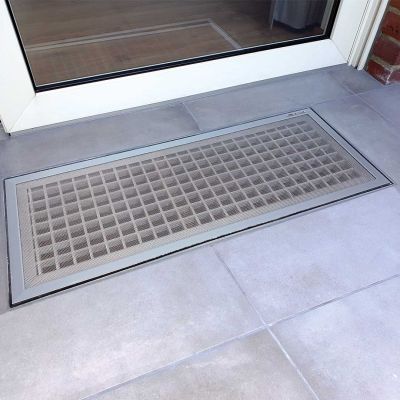 Gitterrost zwischen grauen Fliesen vor Türrahmen