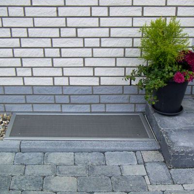 Lichtschachtabdeckung im Außenbereich neben einer Pflanze.