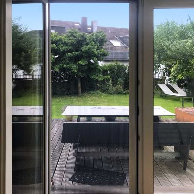 Terrassentür mit Fliegengitter mit Blick zum grünen Garten.