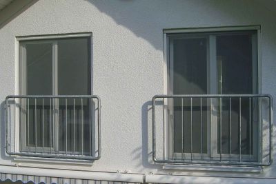 Fenster, mit Fliegengittern an heller Gebäudefassade mit Metallgeländer