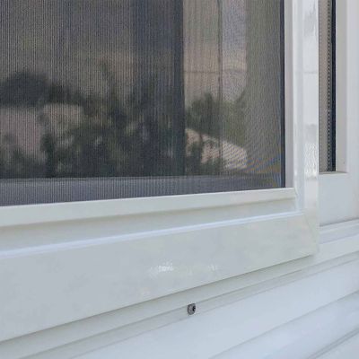 Fliegengitterschiebetür an weißem Fensterrahmen außen