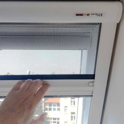 Hand zieht Insektenschutz herunter, montiert am Fensterrahmen.