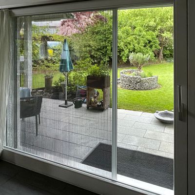 Fliegengittertür mit Garten im Hintergrund.