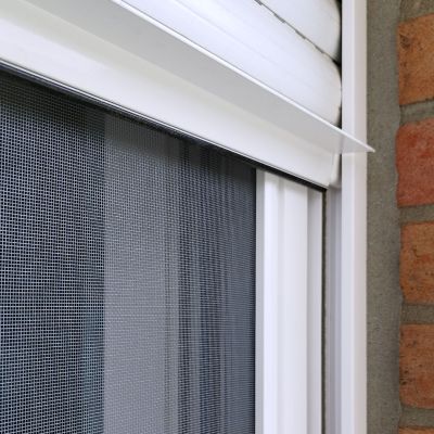 Insektenschutzgitter, befestigt, vor Fenster neben Ziegelmauer.