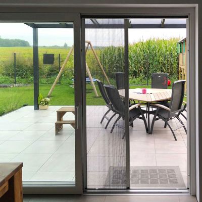 Offenes Insektenschutzplissee führt zu einer Garten-Terrasse.