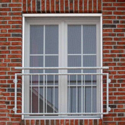 Geschlossenes Fenster mit Fliegengitter in roter Ziegelmauer.
