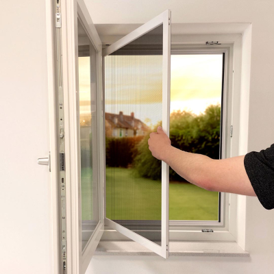 Arm öffnet Fliegengitter Tür in bereits geöffnetem Fenster, Blick in Garten.