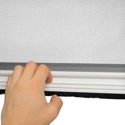 Hand justiert Fliegengitter in einem Fensterrahmen.