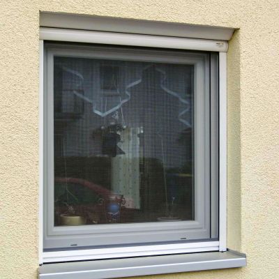 Fenster, mit Fliegengitter ausgestattet, in beiger Hauswand.