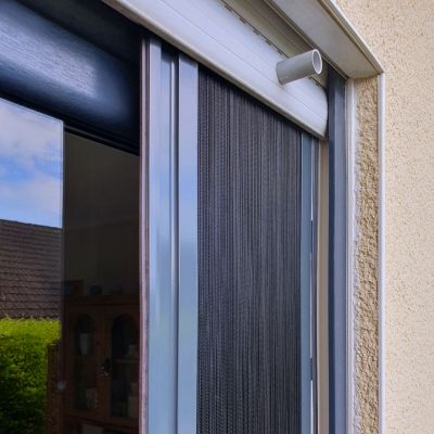 Fliegengitter, befestigt, an Terrassentür bei Tageslicht draußen.